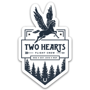 Sticker in a badge shape featuring a pegasus soaring over the words "TWO HEARTS FLIGHT CREW" with evergreen trees below and a horseshoe 